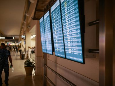 Airport terminal with digital flight information boards showing arrivals and departures.