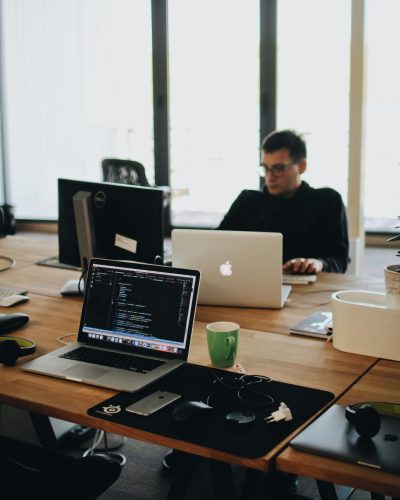 A web developer working on code in a modern office setting with multiple devices.