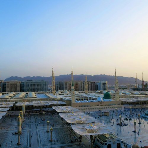Aerial view of Al-Masjid an-Nabawi with minarets at sunset in Medina, Saudi Arabia.
