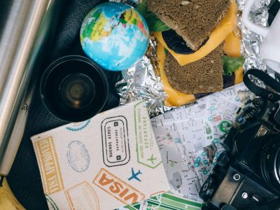 Flat lay of travel essentials with camera and snacks, perfect for a journey.