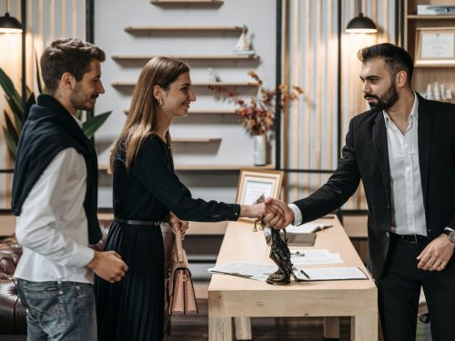 A professional meeting in a modern office with a couple shaking hands with a businessman.